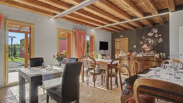 A dining area with wooden furniture, a television, and a kitchen area with wooden cabinets.