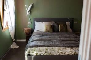 Een slaapkamer met een bed, een trommelstoel en een sculptuur aan de muur.