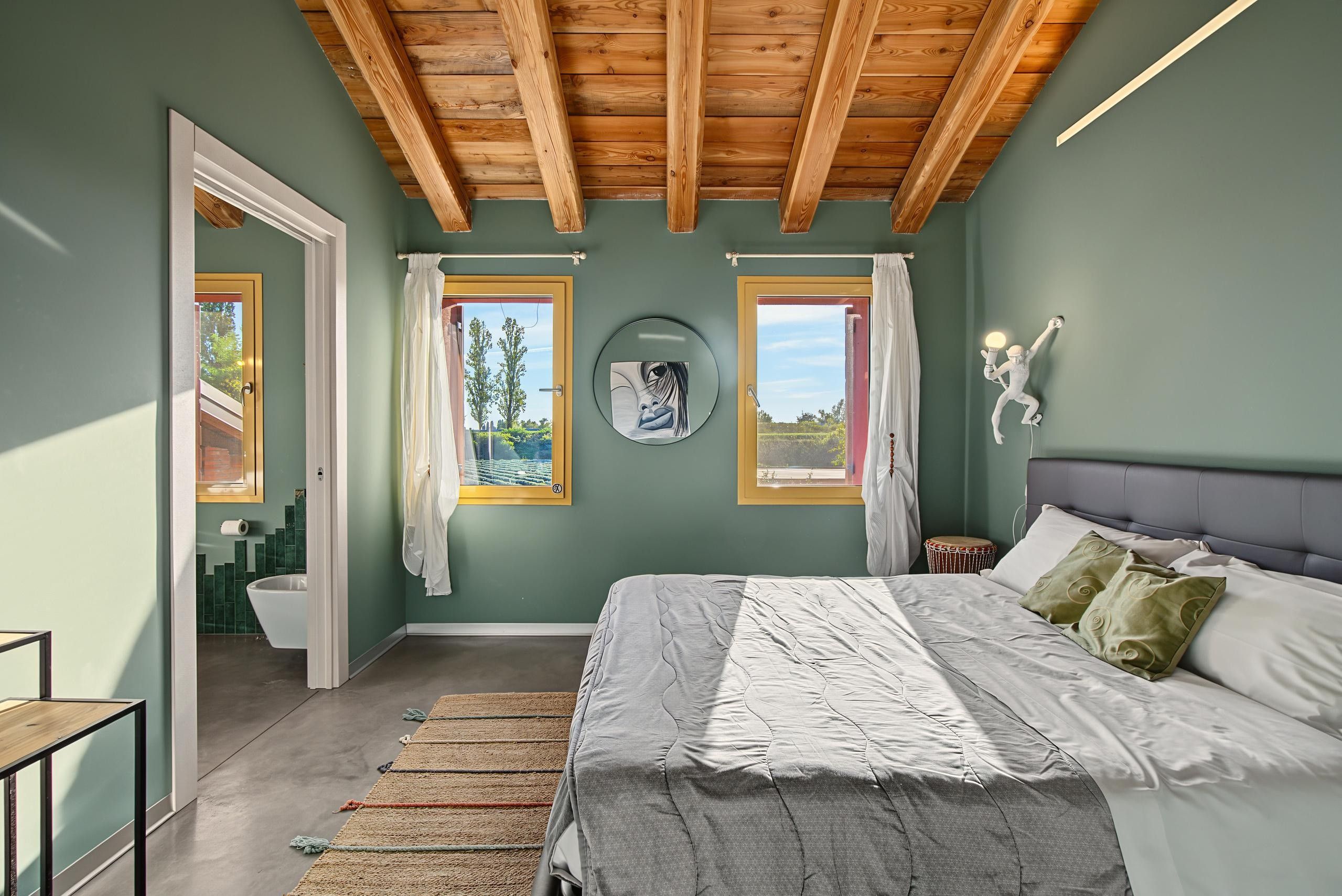 A bedroom with a bed, a window, a door, and a view of the outdoors.