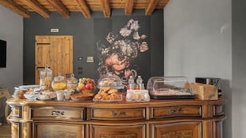 A buffet setup with various food items and a floral mural on the wall.