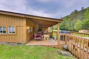 Uma cabana de madeira com varanda coberta, área de refeições e churrasqueira.