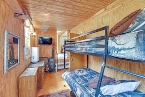 Ein Stockbett mit Bergdekor, ein an der Wand befestigtes Fernsehgerät und eine Holzvertäfelung.