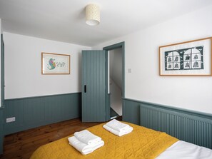 A bedroom with a bed, a door, and two framed pictures on the walls. - Old Anchor Cottage - UK51953 (Broadstairs)