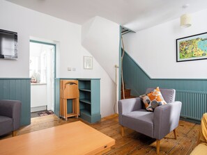 Uma sala de estar moderna com escada, sofá, mesa de centro de madeira e um mapa na parede.