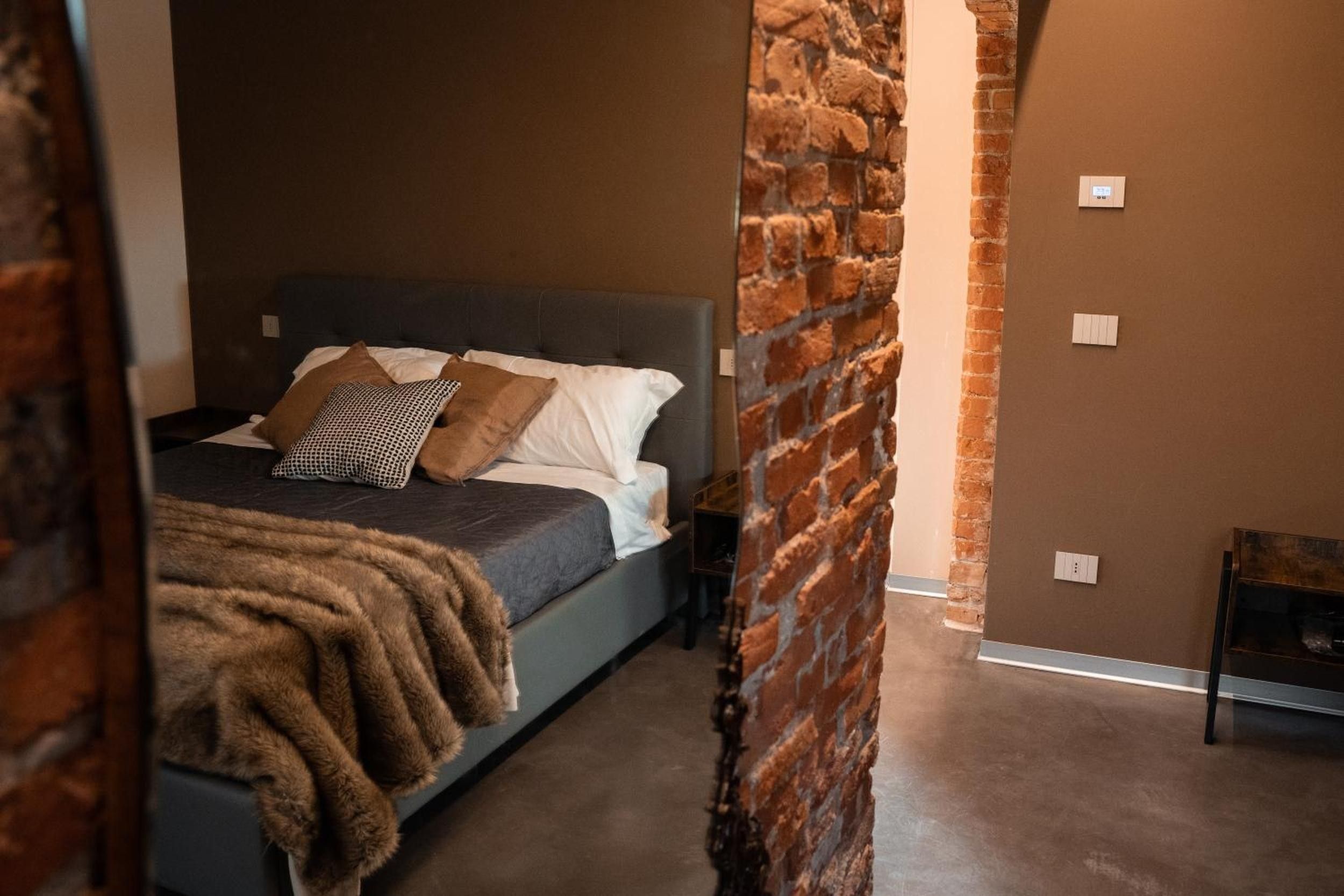 Ein Schlafzimmer mit einem Bett, Kissen, einer Decke und einer Ziegelwand.