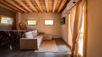 Una stanza accogliente con soffitto in legno, un divano, un tavolino e una televisione.