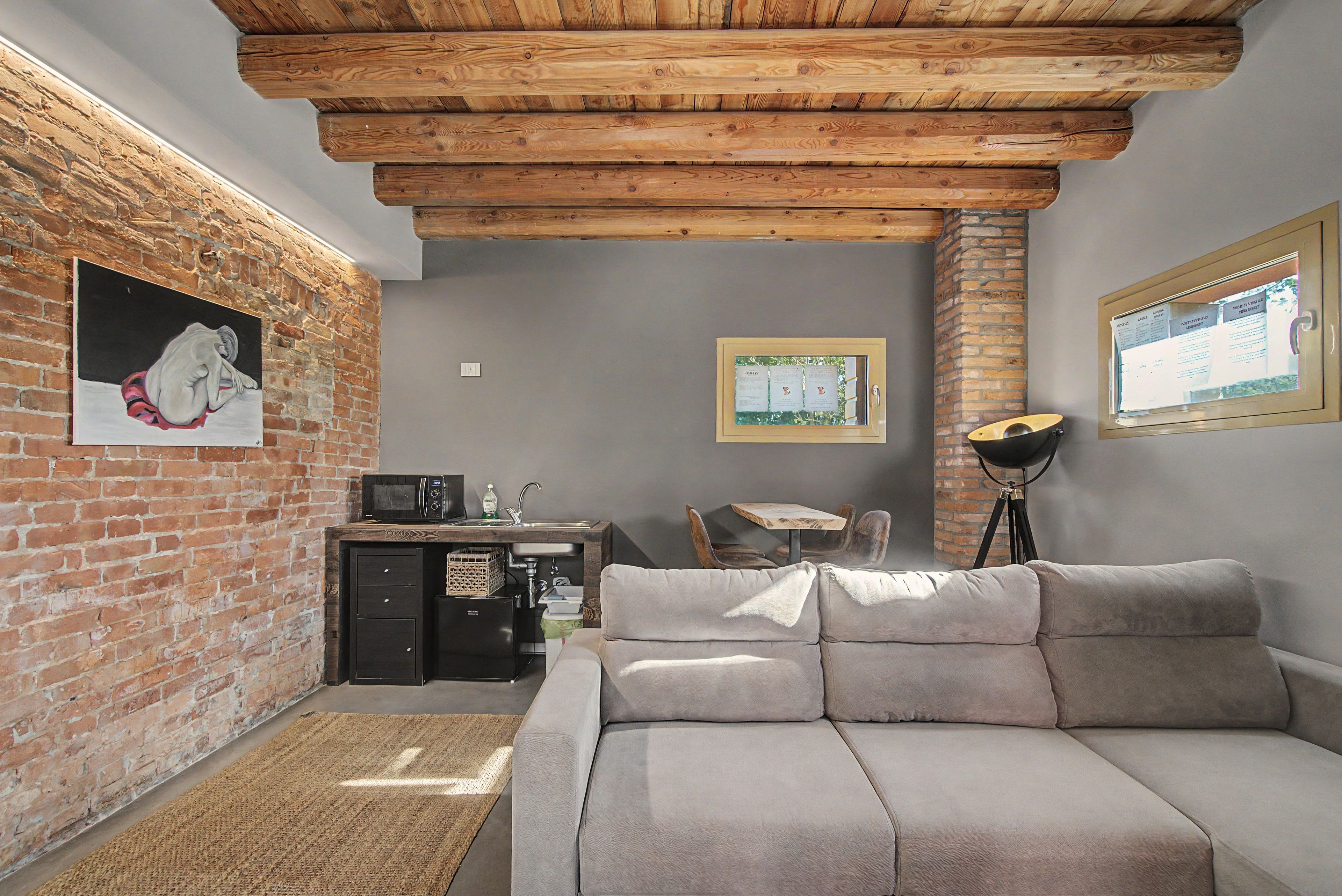 Un salon confortable avec un canapé, une petite kitchenette et un mur en briques.