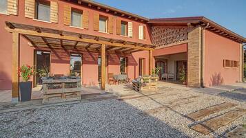 Un bâtiment doté d’un patio couvert, de meubles en bois et de plantes en pot.