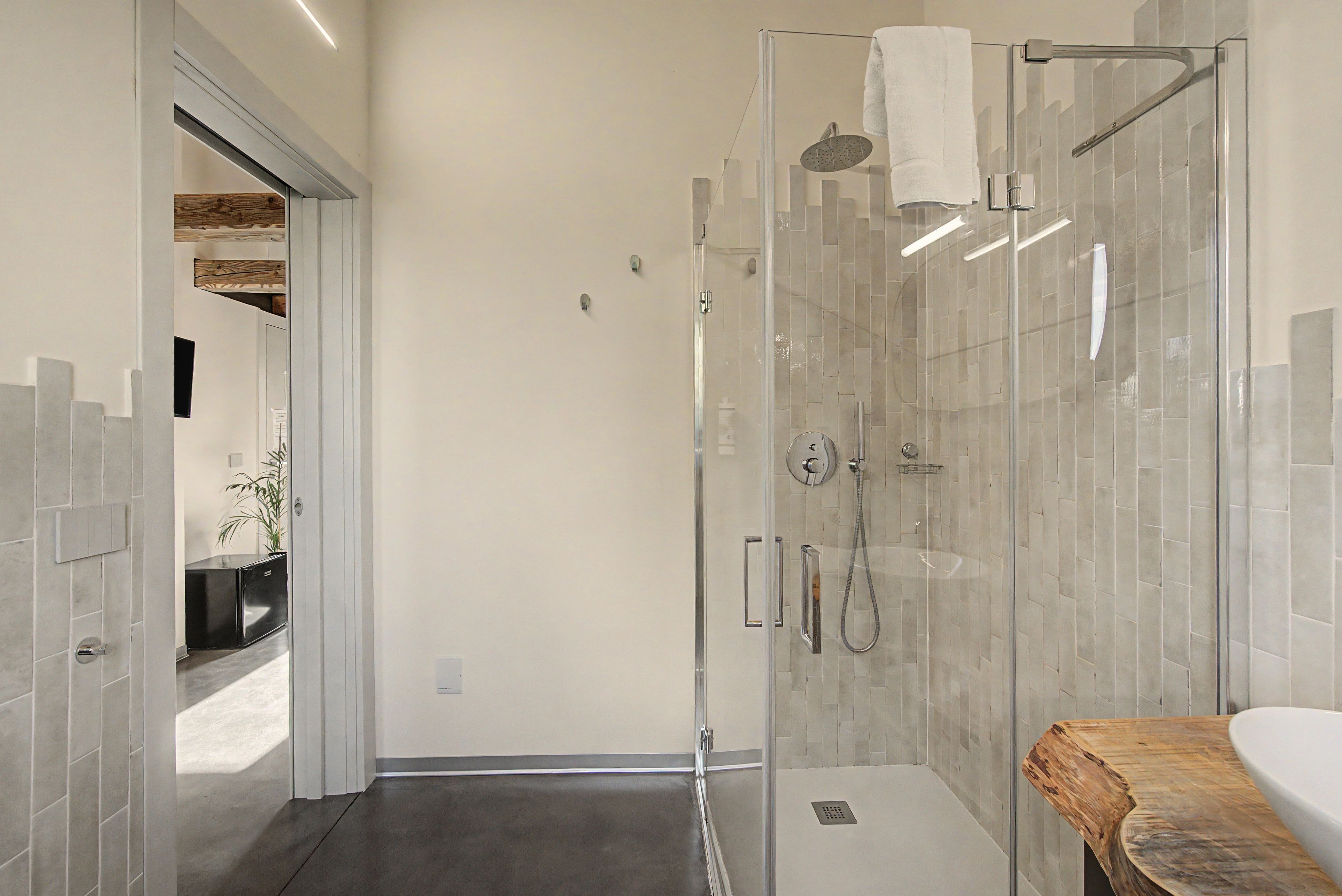 Un bagno moderno con cabina doccia in vetro, mobile bagno in legno e pavimento piastrellato.