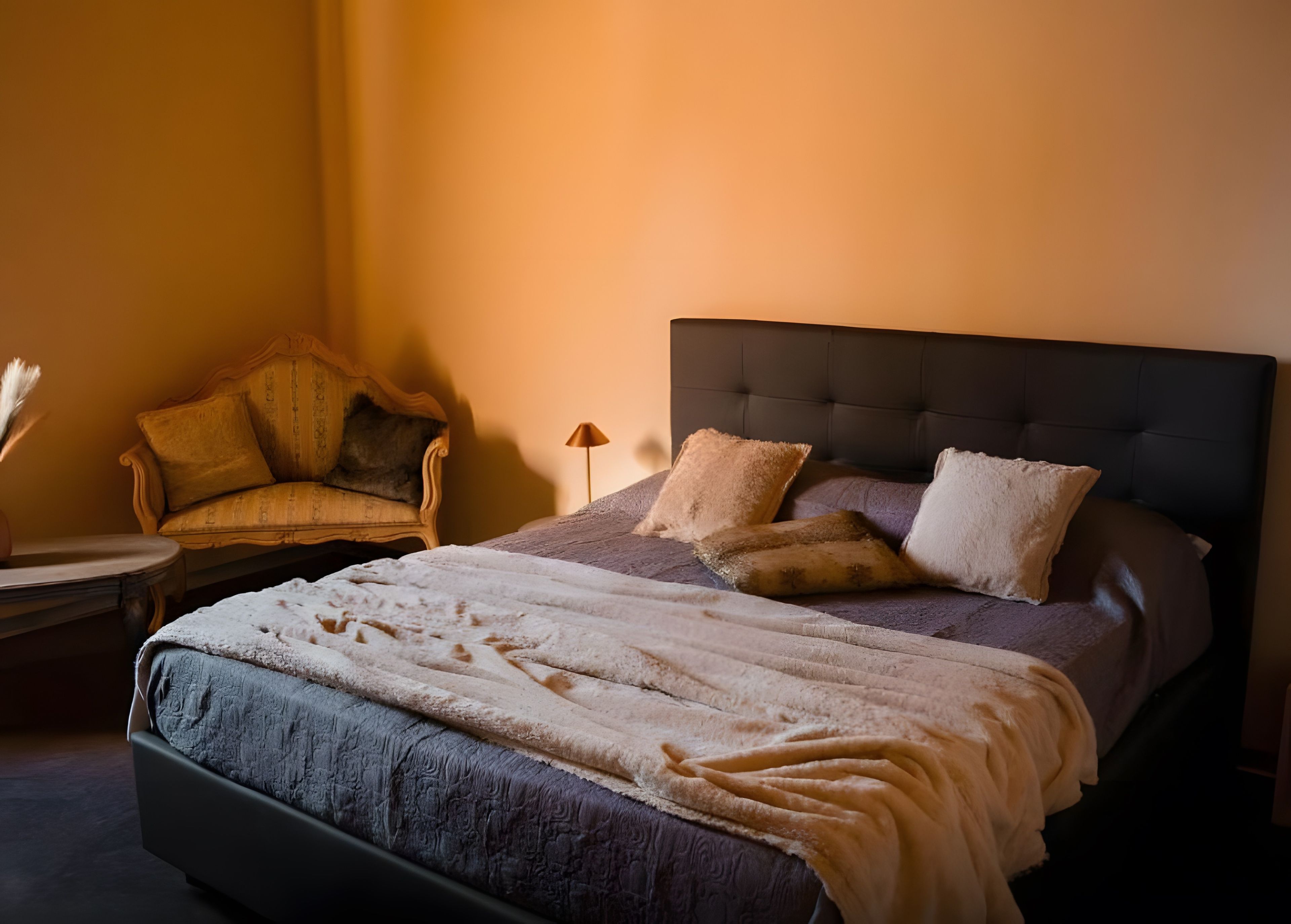 Een bed met een donker hoofdbord, meerdere kussens en een dekbed.