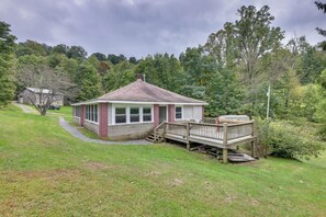 A small, single-story house with a porch and a deck, surrounded by a grassy yard and trees. - Rural WV Escape w/ Hilltop Mountain Views (Tallmansville)