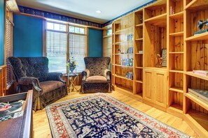 A room with two armchairs, a wooden bookshelf, and a patterned rug. - Log Home on Tipsico Lake w/ Beach & Dock (Holly)