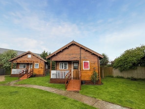 Two wooden cabins with a deck, a small window, and a red sign. - Log Cabin Three - UK51961 (Sutton-on-Sea)