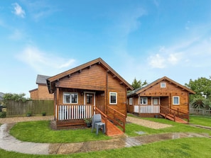 Two wooden cabins with a porch and a staircase leading to the entrance. - Log Cabin Five - UK51963 (Sutton-on-Sea)