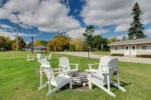 A grassy area with white Adirondack chairs and a fire pit. - Lake Huron Cabin Suite w/ Beach Access (Greenbush)
