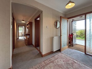 A hallway with a carpet, a radiator, a mirror, and a door leading to an outdoor area. - Roanbank - The Hidden Road Retreat (Castle Douglas)