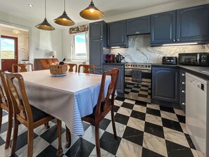A kitchen with a checkered floor, a dining table with chairs, and modern appliances. - Roanbank - The Hidden Road Retreat (Castle Douglas)