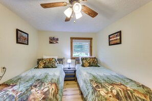 A bedroom with two beds, a ceiling fan, a window, and wall-mounted artwork. - Fish the Right Fork River: Tallmansville Home (Tallmansville)