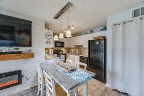 A modern kitchen with a dining area, equipped with a refrigerator, stove, microwave, and pendant lights. - Walk to Beach & Northside Park! Monthly Stay Condo (Ocean City)