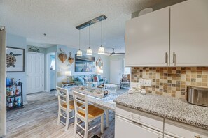 A modern kitchen with a central island, pendant lighting, and a view into the adjacent dining area. - Walk to Beach & Northside Park! Monthly Stay Condo (Ocean City)
