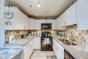 A kitchen with white cabinets, a microwave, a stove, and a sink. - Walk to Beach & Northside Park! Monthly Stay Condo (Ocean City)