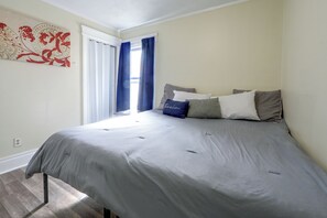 A bedroom with a bed, pillows, a window with curtains, and a wall with a floral pattern. - Walk to Rosamond Gifford Zoo & Dining! Cozy Unit (Syracuse)