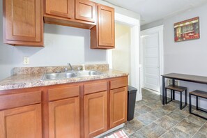A kitchen with wooden cabinets, a granite countertop, a double sink, and a small dining table with chairs. - Walk to Rosamond Gifford Zoo & Dining! Cozy Unit (Syracuse)