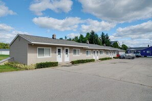 A single-story motel with a row of rooms, a parking area, and a clear sky. - Beach Access! Sunrise Side Resort Retreat (Greenbush)