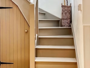 A staircase with a wooden door and a wicker basket on the landing. - Hen Stabal - UK51984 (Llanfair, near Harlech)