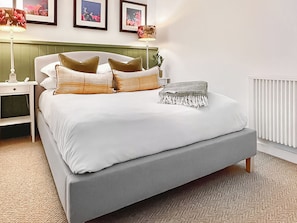 A neatly made bed with a grey mattress, white linens, and multiple pillows in shades of brown and beige. - Hen Stabal - UK51984 (Llanfair, near Harlech)