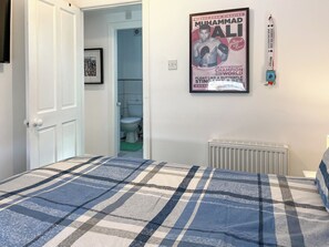 A bedroom with a bed, a poster on the wall, a radiator, and a door leading to a bathroom. - 2 bedroom accommodation in Killham (Killham)