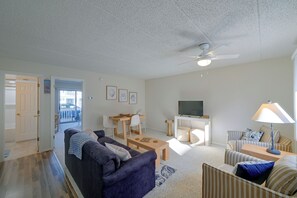A living room with a dark sofa, a coffee table, a TV, and a ceiling fan. - Walk to Beach! Updated Brigantine Retreat (Brigantine)