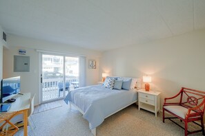 A bedroom with a bed, a desk with a computer, a chair, a nightstand with a lamp, and a view of the outside. - Walk to Beach! Updated Brigantine Retreat (Brigantine)