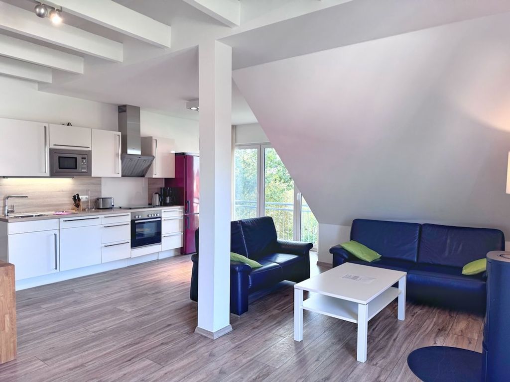 Et moderne køkken med hvide skabe og et spiseområde med en blå sofa og et hvidt bord.