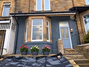 A townhouse with a bay window, a front door, and three potted plants on the stoop. - Beautiful & Cosy Newly Renovated House in Blaydon (Blaydon)