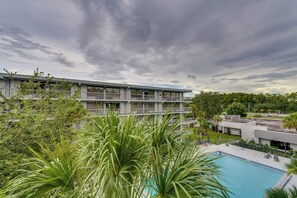 Un hôtel à plusieurs étages doté d’un espace piscine, entouré de verdure et d’arbres.