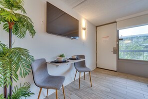 Ein modernes Zimmer mit Essecke, ausgestattet mit zwei grauen Stühlen, einem kleinen Tisch und einem Blumentopf.