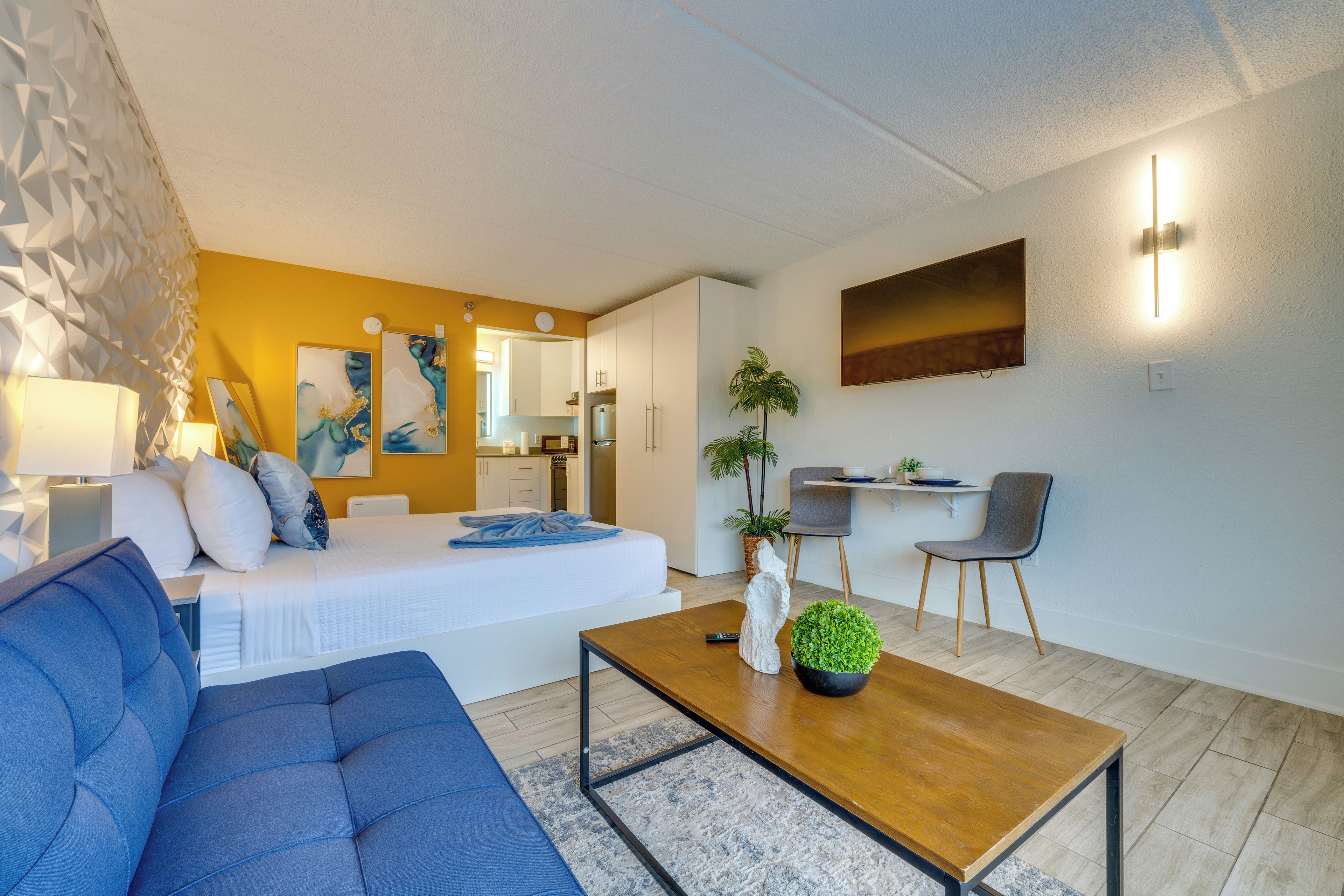 A modern living room with a sofa, a coffee table, a bed, and a dining area with a chair and table.