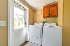 A laundry room with two white front-loading washers and dryers, wooden cabinets above, and a door with a window. - 22-Acre Farm Retreat < 8 Mi to Kentucky Lake! (Dexter)