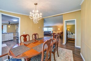 A spacious dining area with a wooden table and chairs, a chandelier, and a view into the living room. - 22-Acre Farm Retreat < 8 Mi to Kentucky Lake! (Dexter)