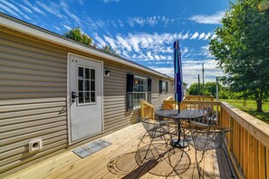 Une maison mobile dotée d’une terrasse, d’un paillasson et d’une table de patio avec des chaises.