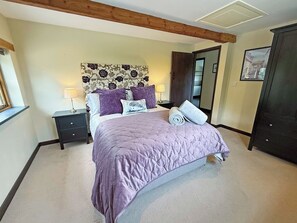 A bedroom with a bed, two bedside tables, a nightstand, a headboard with a floral pattern, and a door. - 2 bedroom accommodation in Holsworthy (Holsworthy)