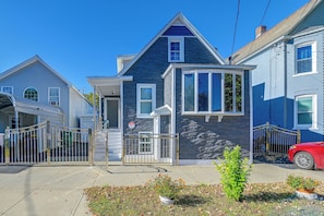 A residential property with a gated entrance, a garage, and a red car parked on the street. - Updated Schenectady Home: 1 Mi to Downtown! (Schenectady)