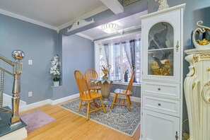 A dining area with a round table, two wooden chairs, a chandelier, and a white cabinet with a gold eagle decoration. - Updated Schenectady Home: 1 Mi to Downtown! (Schenectady)