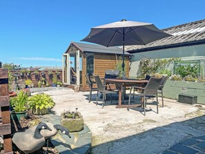 A patio with a table and chairs, a grill, and a large umbrella. - Another Dawn - UK52026 (Wigton)