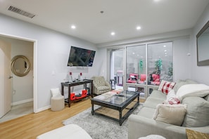 A modern living room with a flat-screen TV mounted on the wall, a coffee table, a sofa, and a chair. - Viva La Dolce Vita in the Heart of Little Italy! (San Diego)