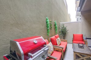 Ein roter Grill, rote Gartenmöbel und ein Blumentopf an einer Wand.