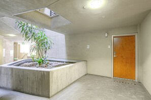 A modern interior with a concrete planter, a wooden door, and a ceiling light fixture. - Viva La Dolce Vita in the Heart of Little Italy! (San Diego)
