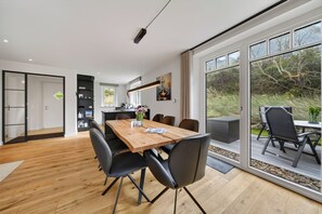 Une cuisine moderne avec un coin repas, de grandes fenêtres et une vue sur l’extérieur.