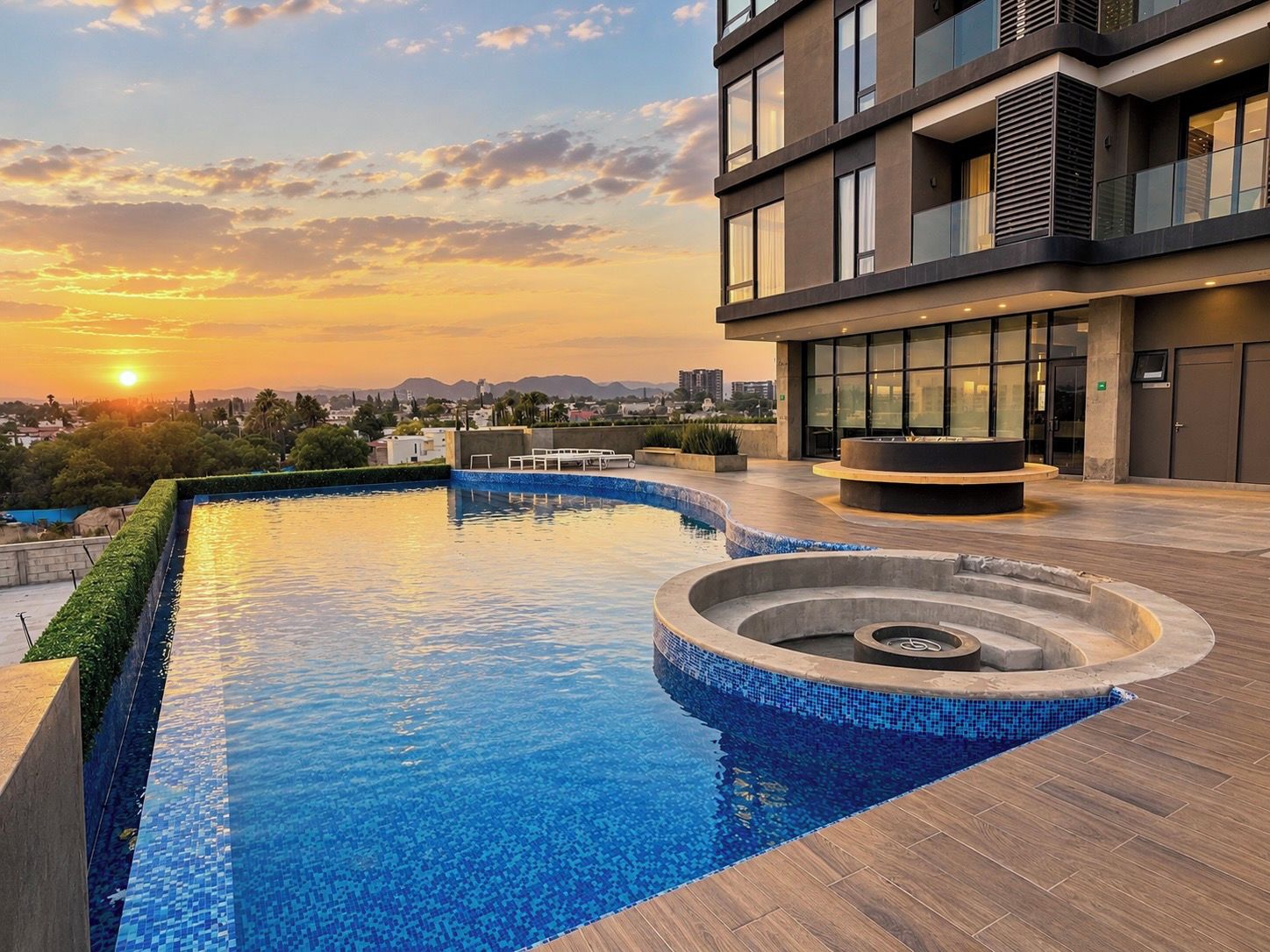 A rooftop swimming pool with a modern design, surrounded by a building with large windows and a view of the sunset.